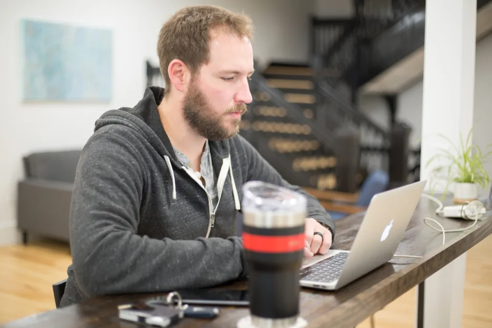 Office workers at their desks — the everyday setting PACT recreates, where an assistant's standing compliance rule collides with a colleague's deadline.